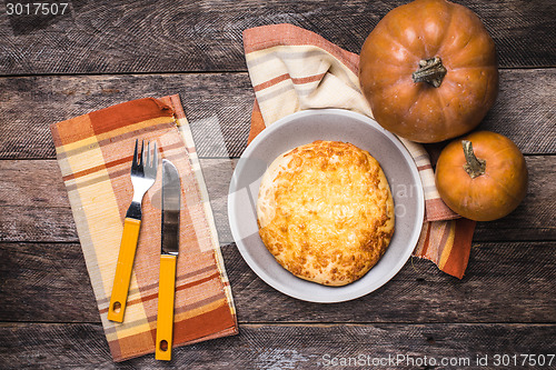 Image of Rustic style pumpkins and flat cake on wooden table