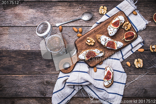 Image of Bruschetta with figs and nuts on board in rustic style