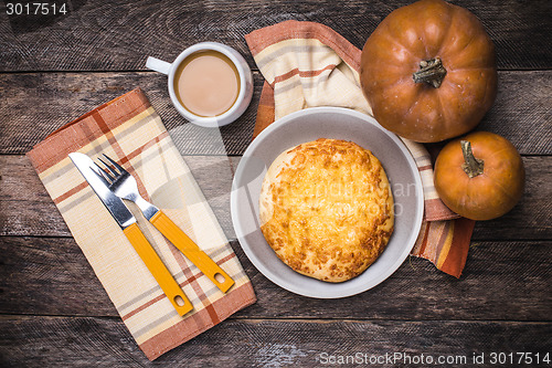 Image of Pumpkins, coffee and flat cake on wooden table