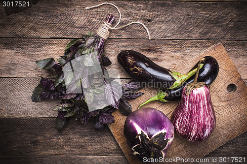 Image of Rustic style Aubergines and basil on chopping board 