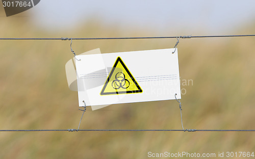 Image of Border fence - Old plastic sign with a flag