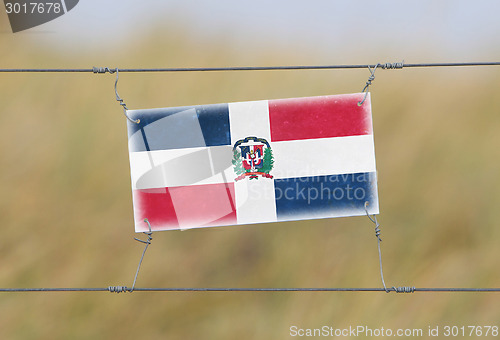 Image of Border fence - Old plastic sign with a flag