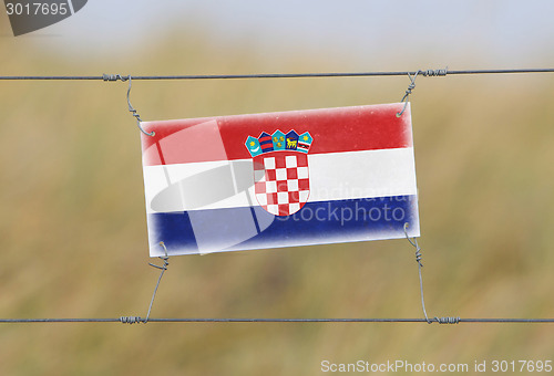 Image of Border fence - Old plastic sign with a flag