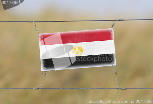 Image of Border fence - Old plastic sign with a flag