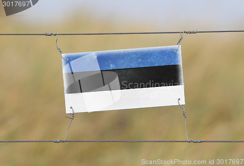 Image of Border fence - Old plastic sign with a flag