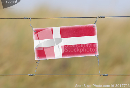 Image of Border fence - Old plastic sign with a flag