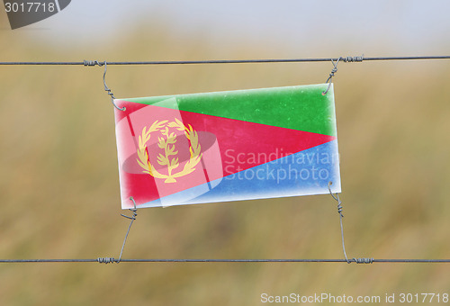 Image of Border fence - Old plastic sign with a flag