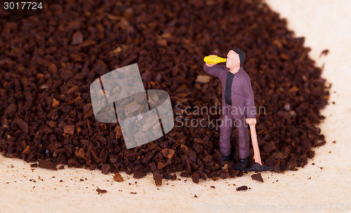 Image of Miniature worker working on grinded coffee