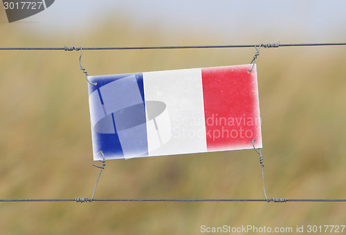 Image of Border fence - Old plastic sign with a flag