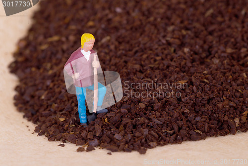 Image of Miniature worker working on grinded coffee