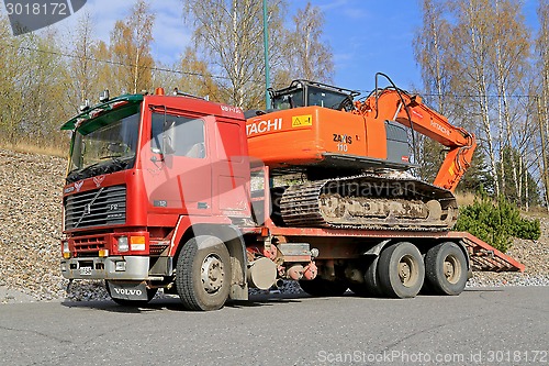 Image of Red Volvo F12 Intercooler Hauls a Hitachi Zaxis Excavator