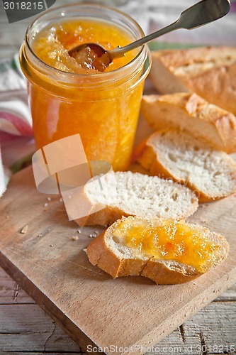 Image of orange jam in a glass jar and bread