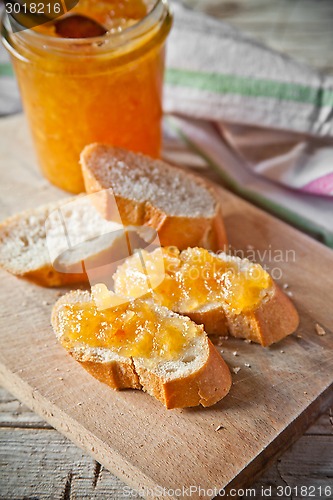 Image of orange jam in a glass jar and bread