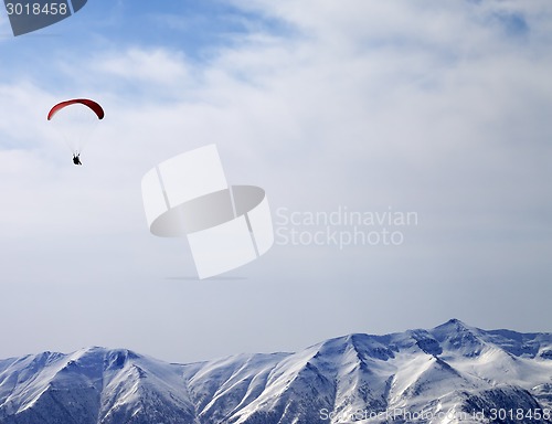 Image of Paraglider silhouette of mountains in sunlight sky