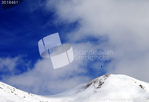 Image of Paraglider silhouette of mountains in windy sky