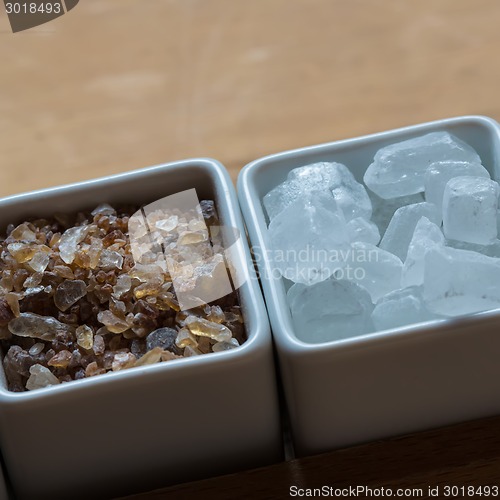 Image of white and brown sugar on wooden table.