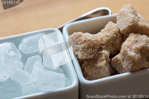 Image of white and brown sugar on wooden table.