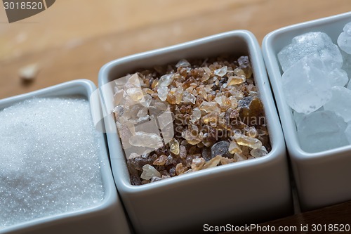 Image of white and brown sugar on wooden table.