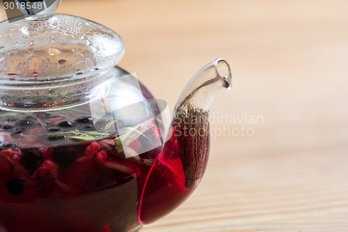 Image of Hot tea with berries on wooden table