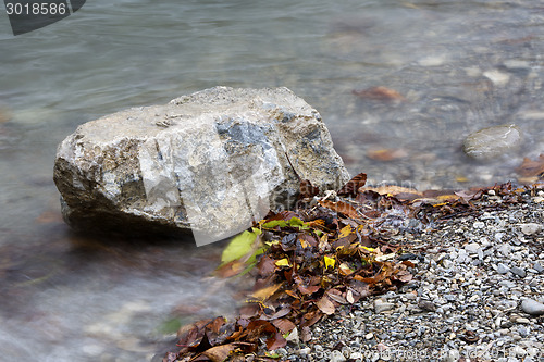 Image of Stone in a lake in autumn with colorful leaves