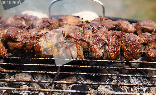 Image of Closeup of beef meat on skewers over hot charcoal barbecue