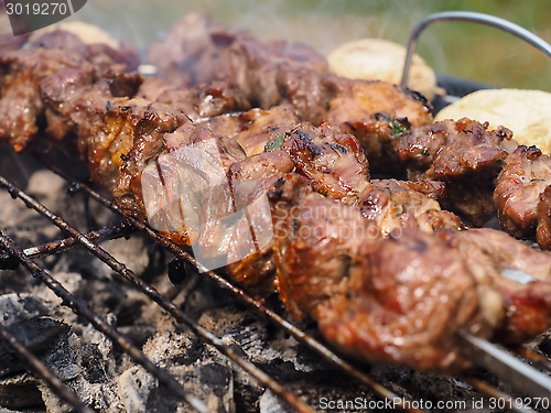 Image of Closeup of beef meat on skewers over hot charcoal barbecue