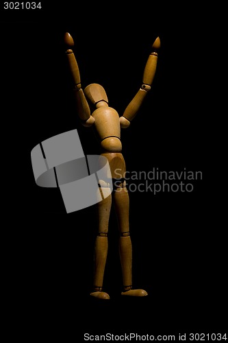 Image of Wooden mannequin raising hands to light isolated on black.