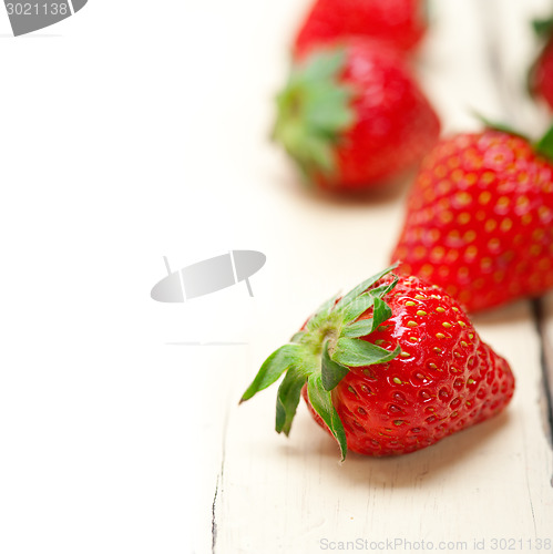 Image of fresh organic strawberry over white wood