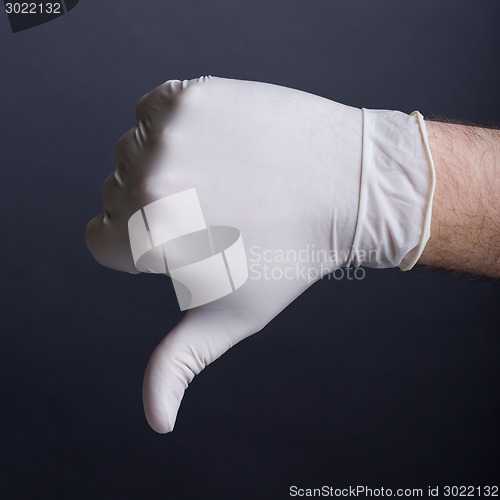 Image of Male hand in latex glove (thumb down sign)