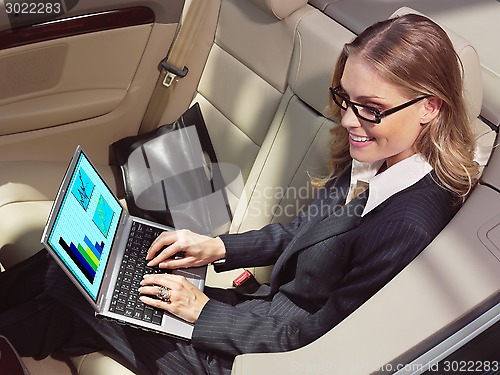 Image of businesswoman in her car with laptop