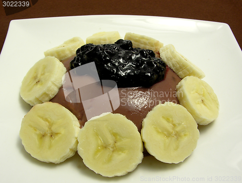 Image of Chocolate pudding arranged with banana slices and blueberry jam on a white plate
