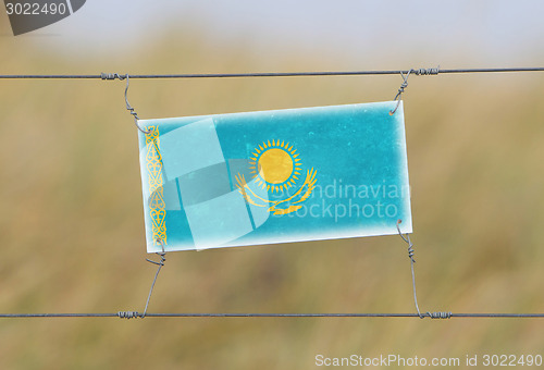 Image of Border fence - Old plastic sign with a flag