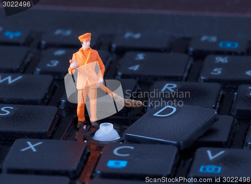 Image of Miniature worker with broom working on keyboard