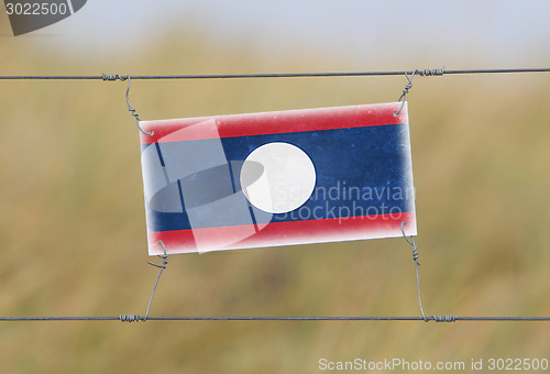 Image of Border fence - Old plastic sign with a flag