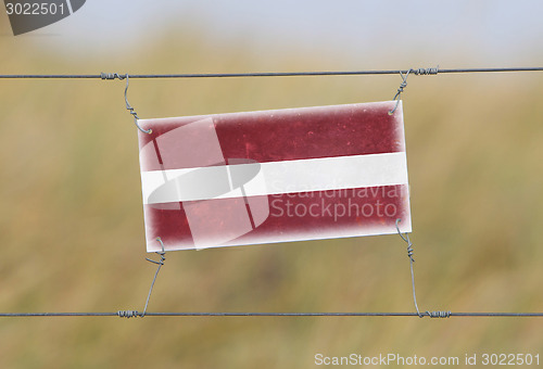 Image of Border fence - Old plastic sign with a flag