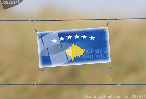 Image of Border fence - Old plastic sign with a flag