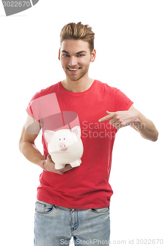 Image of Handsome young man holding a piggy bank