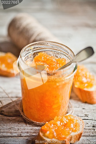 Image of orange jam in a glass jar and bread