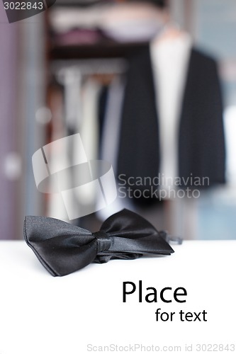 Image of Bow tie. Open closet and tuxedo. 