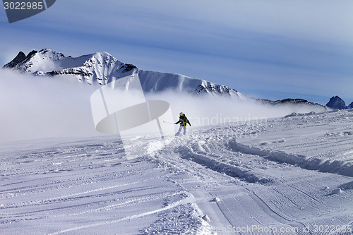Image of Snowboarder downhill on off-piste slope with newly-fallen snow