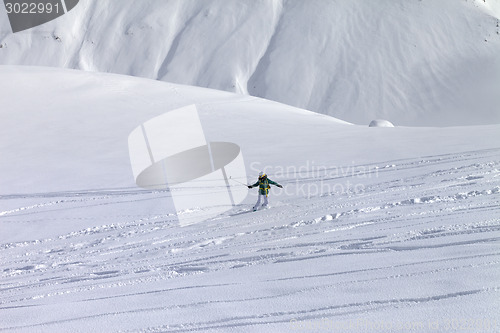Image of Snowboarder downhill on off piste slope with newly-fallen snow
