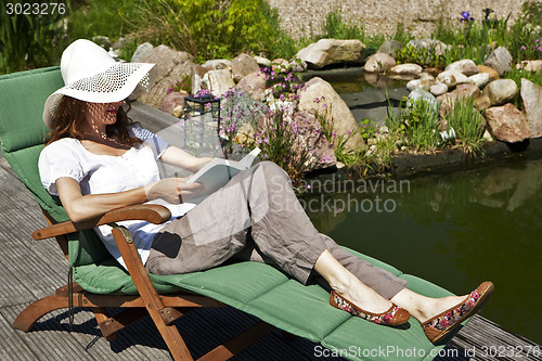 Image of woman reads at the pond