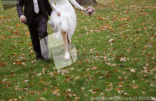 Image of Bride and groom running on grass