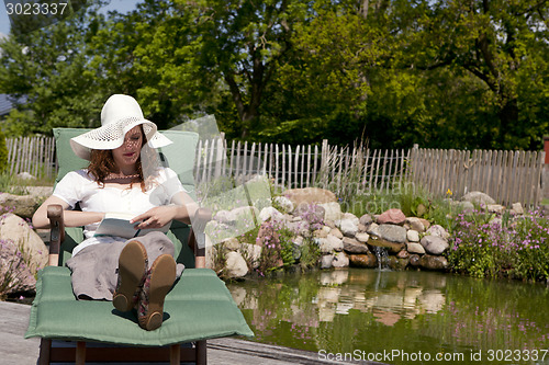 Image of woman enjoys garden pond lies, frau geniesst gartenliege teich