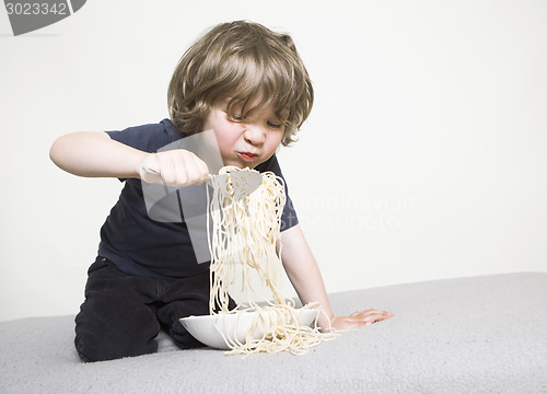 Image of Child eating spaghetti on the sofa