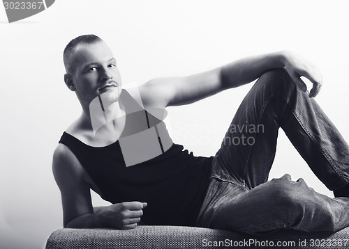 Image of young athletic man lying on a sofa bw