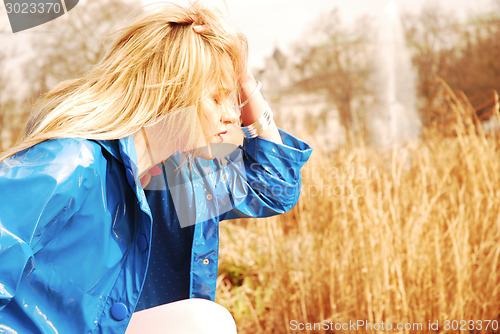 Image of Young Woman wearing blue rain coat