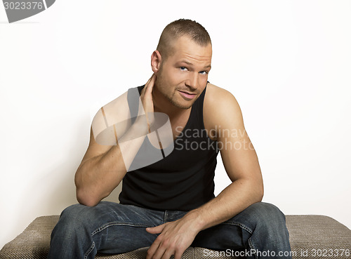 Image of young man sitting with one hand at his head