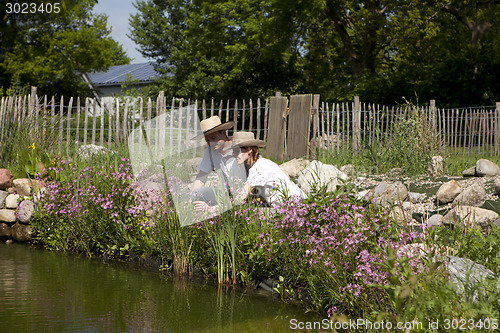 Image of couple with a straw hat on the garden pond, pärchen mit strohhu