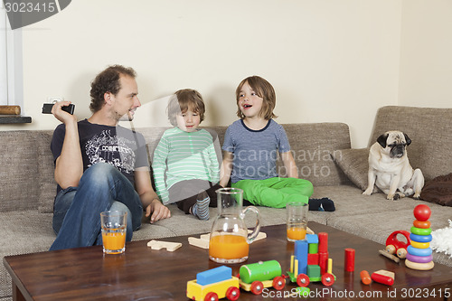 Image of father with sons and dog on sofa